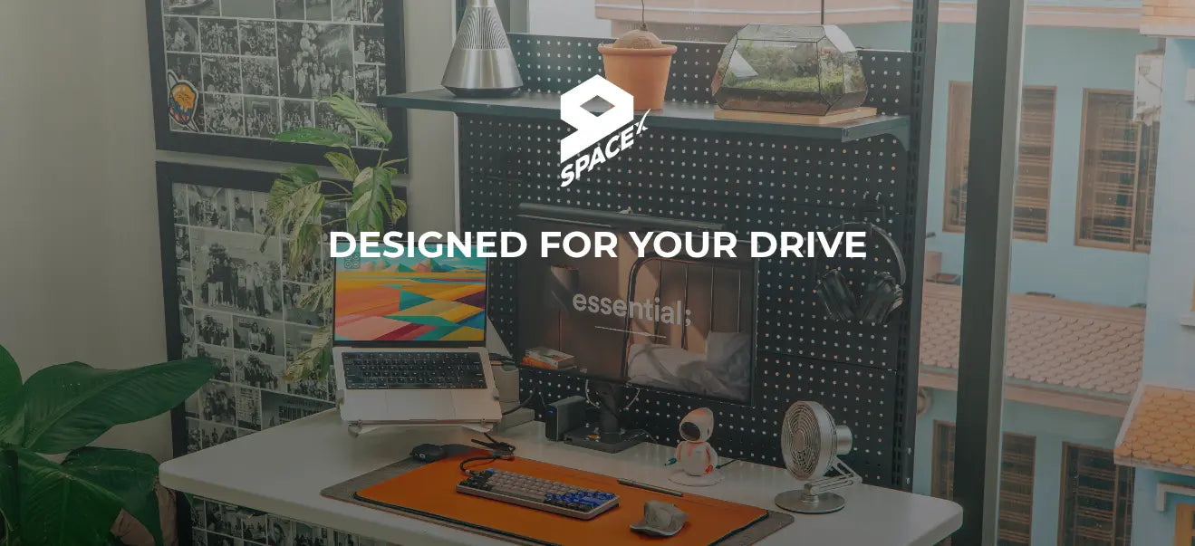 Desk setup with computer equipment and SpaceX logo in a room.